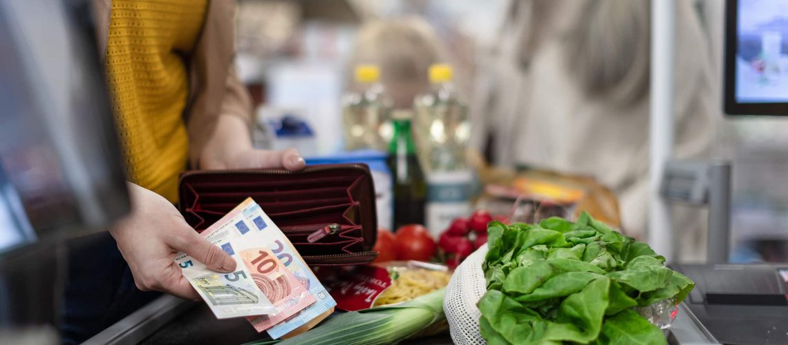 A close-up of woman giving money at the cash desk in supermarket